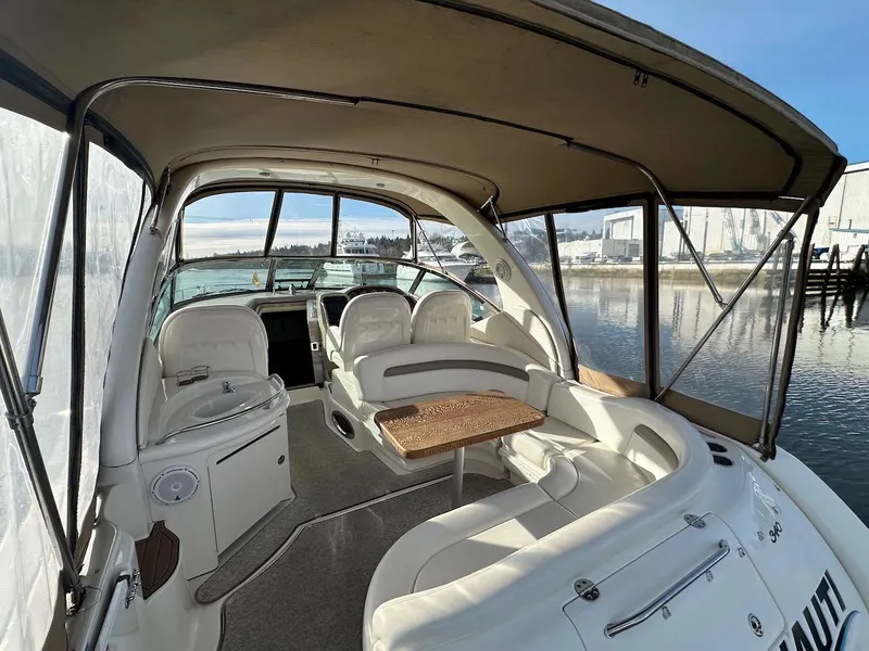 Slide: The Image of 2004 Sea Ray 340 Sundancer boat interior with seating and table, docked by the water. - 21