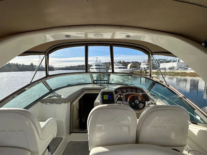 Slide: The Image of 2004 Sea Ray 340 Sundancer cockpit with steering wheel, dashboard, and waterfront view. - 27