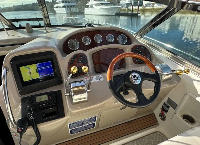 Slide: The Image of 2004 Sea Ray 340 Sundancer helm with navigation system and wooden steering wheel, docked by water. - 31
