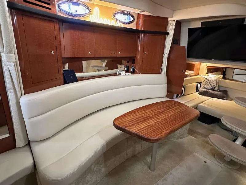 Slide: The Image of 2004 Sea Ray 340 Sundancer interior with curved seating and wooden table. - 40