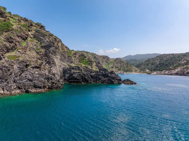 Slide: The Image of Coastal landscape with clear blue water and rocky cliffs under a bright sky. - 10