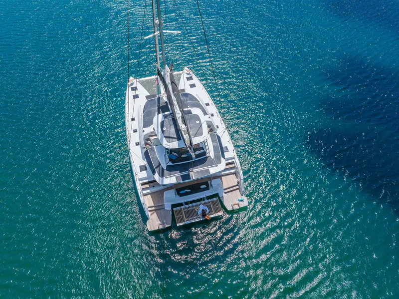 Slide: The Image of Aerial view of 2025 Lagoon 51 ICONIC catamaran sailing on clear blue water. - 13