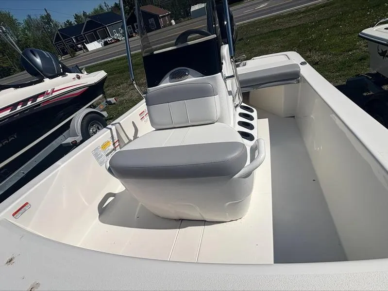Slide: The Image of 2025 Mako SKIFF 13 CC boat interior with seating and console, parked outdoors. - 13