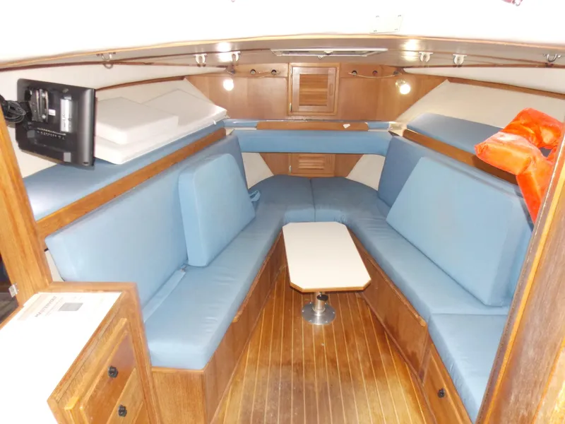 Slide: The Image of 1999 Albemarle 320 Express cabin with blue seating, wooden interior, and compact table. - 14