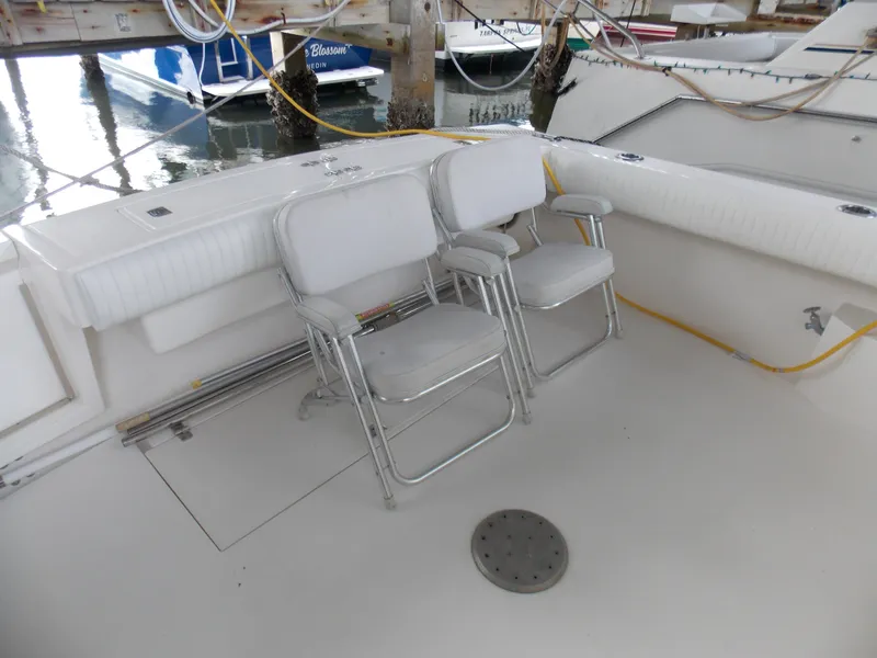 Slide: The Image of 1999 Albemarle 320 Express boat deck with white seating and docked surroundings. - 5