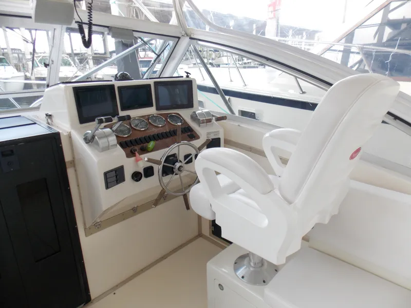 Slide: The Image of 1999 Albemarle 320 Express helm with white captain's chair and navigation instruments. - 7