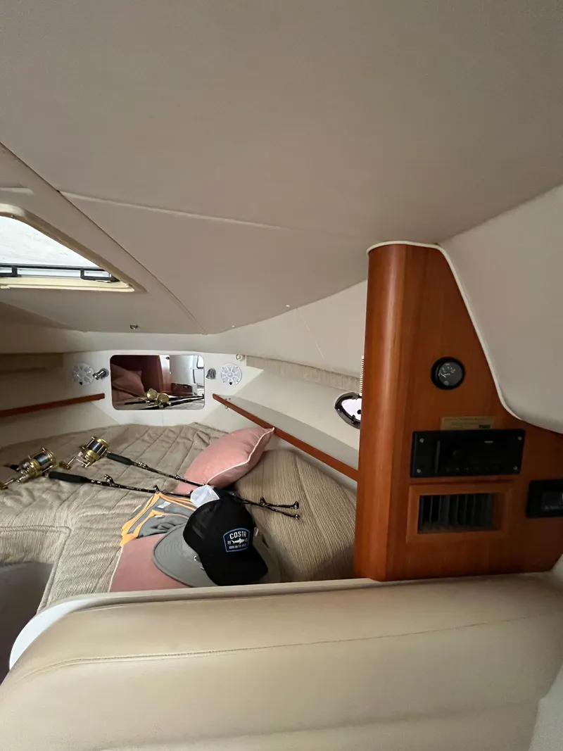Slide: The Image of 2004 Tiara Yachts Classic cabin interior with fishing rods and hats on the bed. - 2