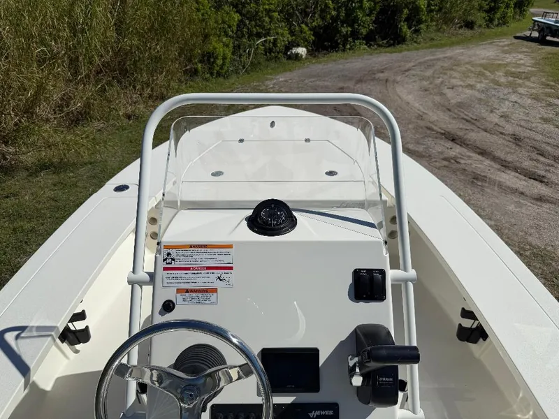 Slide: The Image of 2025 Hewes 16 Redfisher boat dashboard with steering wheel and controls, parked on grassy terrain. - 10