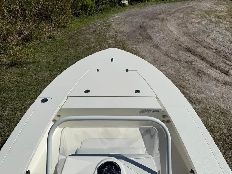 Slide: The Image of 2025 Hewes 16 Redfisher boat on grassy terrain, showcasing sleek design and storage compartment. - 11