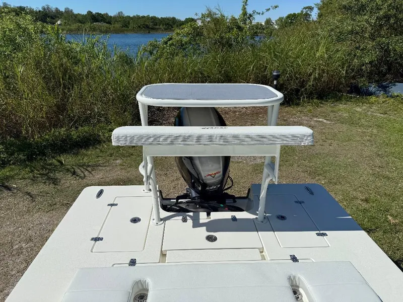 Slide: The Image of 2025 Hewes 16 Redfisher boat, rear view, near a lake with lush greenery. - 13