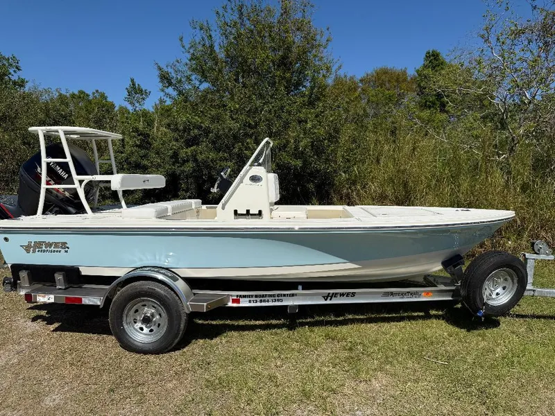 Slide: The Image of 2025 Hewes 16 Redfisher boat on trailer, parked outdoors with trees in background. - 16