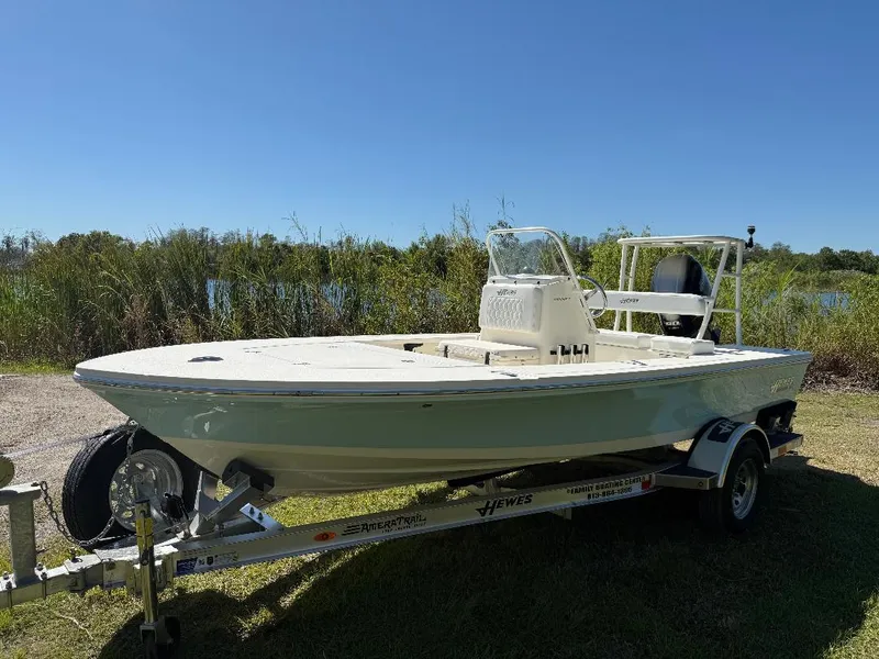 Slide: The Image of 2025 Hewes 16 Redfisher boat on trailer, parked near a lake under clear blue sky. - 18