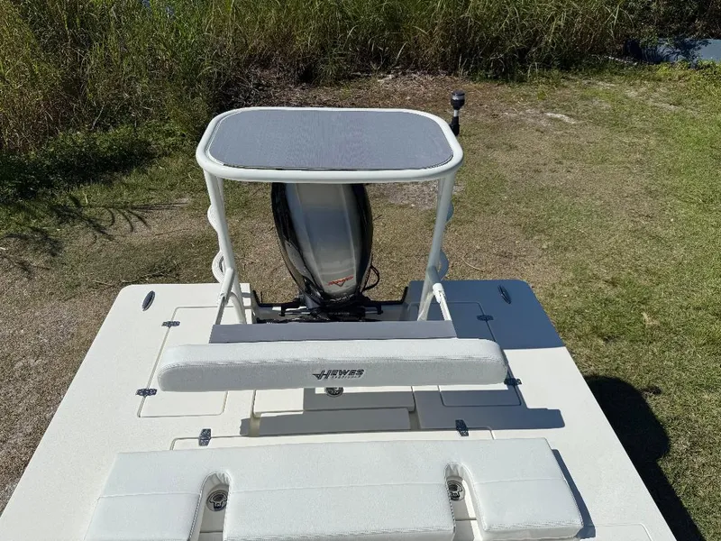 Slide: The Image of 2025 Hewes 16 Redfisher boat on grassy area, showcasing rear seating and motor. - 6