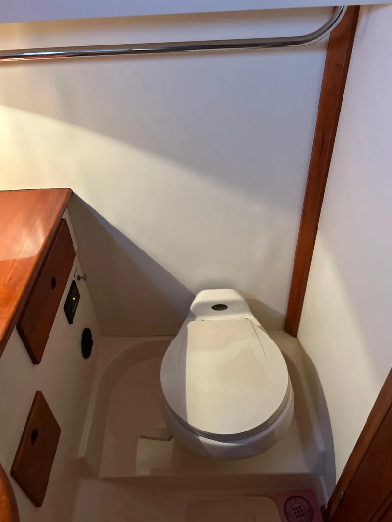 Slide: The Image of 2001 Hinckley Classic 36 Picnic Boat bathroom interior with wooden accents and compact toilet. - 41