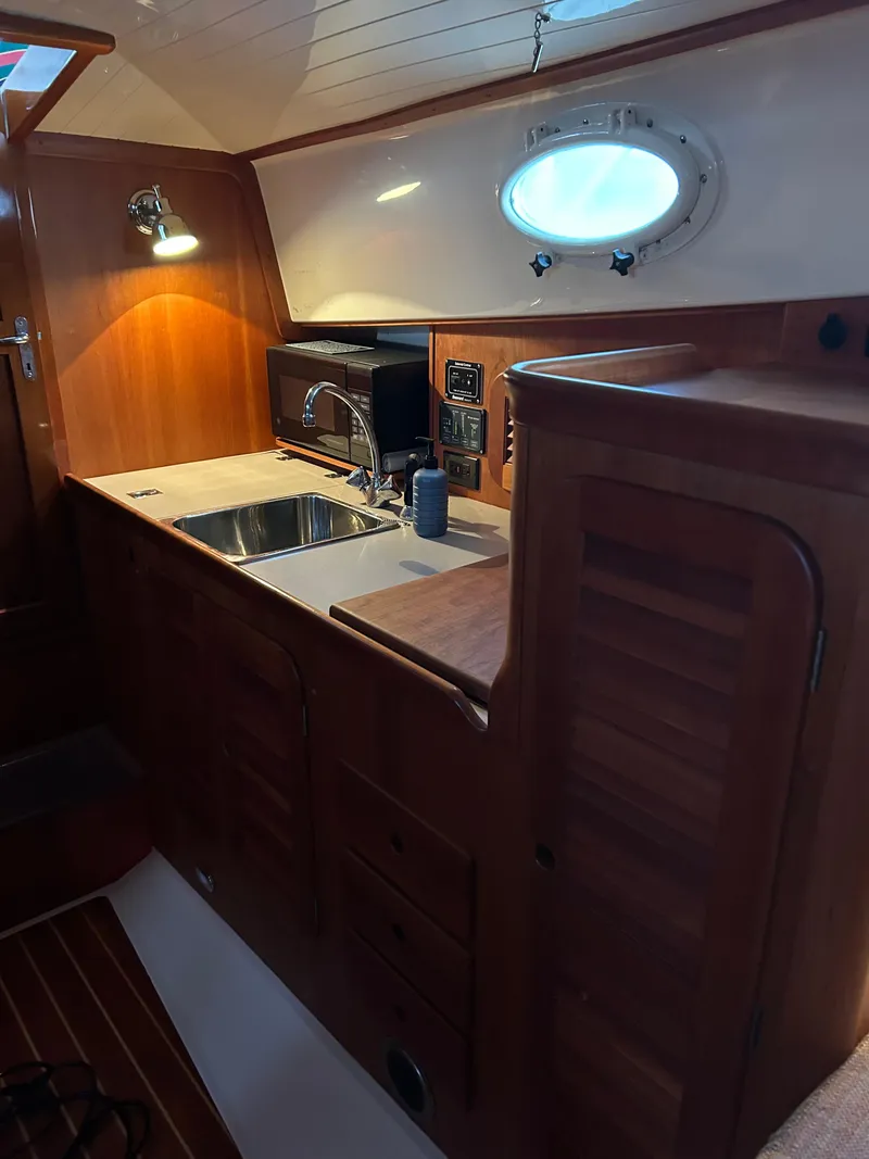 Slide: The Image of 2001 Hinckley Classic 36 Picnic Boat interior with wooden cabinetry and compact kitchen area. - 48