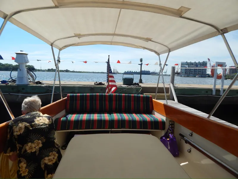 Slide: The Image of Hinckley Classic 36 Picnic Boat, 2001, with striped seating and canopy, docked by the water. - 7