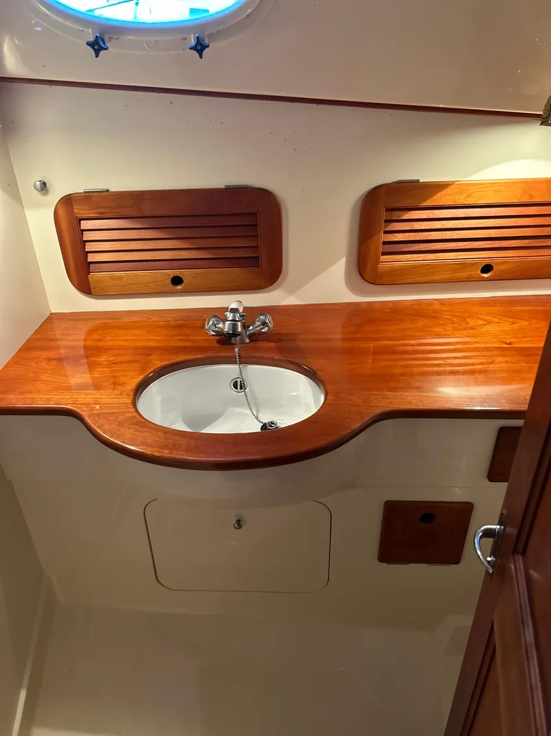 Slide: The Image of 2001 Hinckley Classic 36 Picnic Boat interior with wooden sink area and storage. - 46