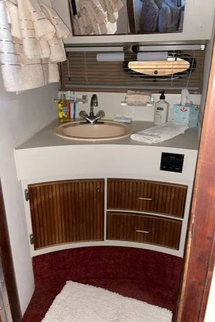 Slide: The Image of 1988 Regal 360 XL Commodore bathroom with updated sink, wooden cabinets, and red carpet. - 12