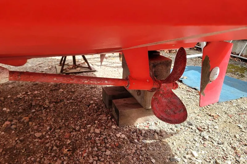 Slide: The Image of Red propeller and rudder of 1988 Regal Commodore 360 on gravel surface. - 35