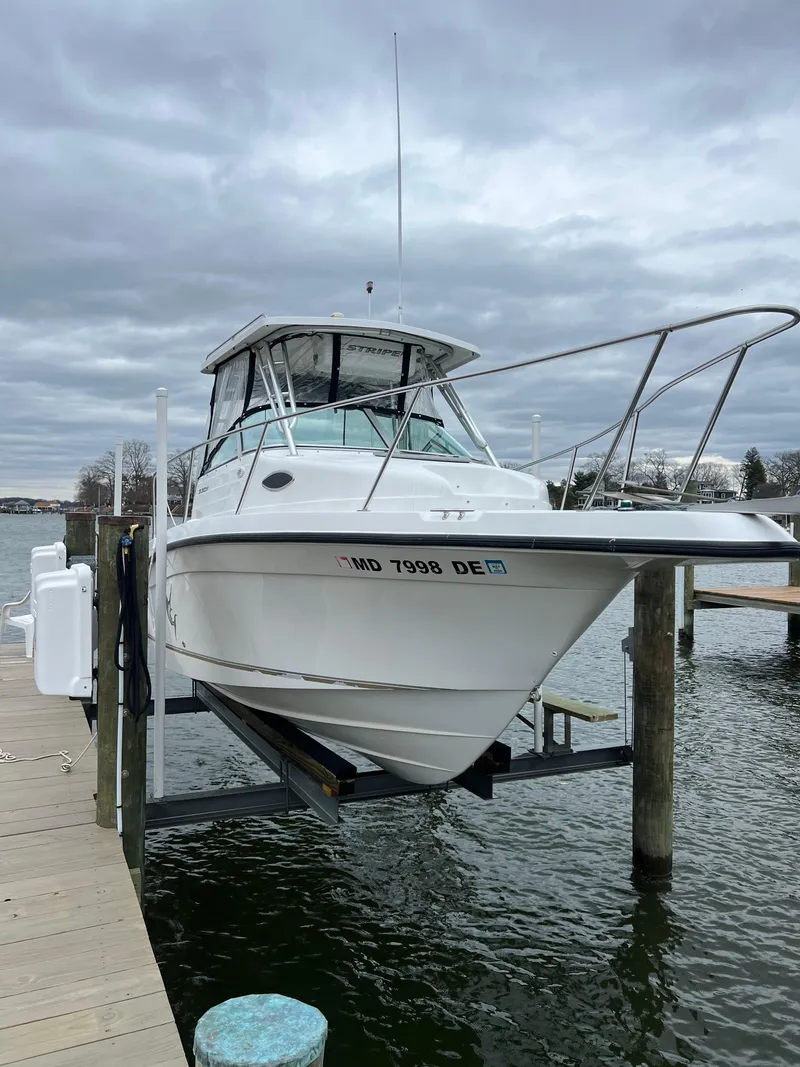 Slide: The Image of 2003 Seaswirl Striper 2301 Walkaround OB on dock lift, cloudy sky background. - 2