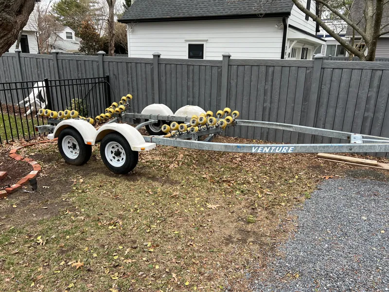 Slide: The Image of Boat trailer for 2003 Seaswirl Striper 2301 Walkaround OB, parked on gravel near a wooden fence. - 22