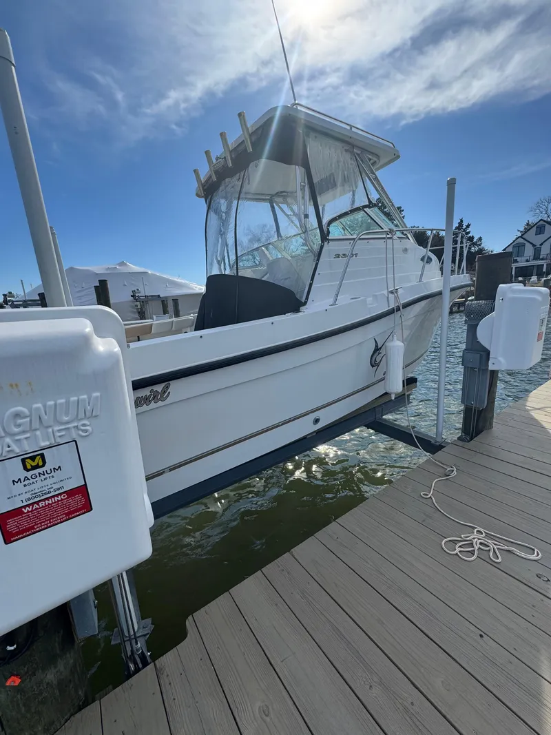 Slide: The Image of 2003 Seaswirl Striper 2301 Walkaround OB docked, showcasing sleek design and fishing capabilities. - 4