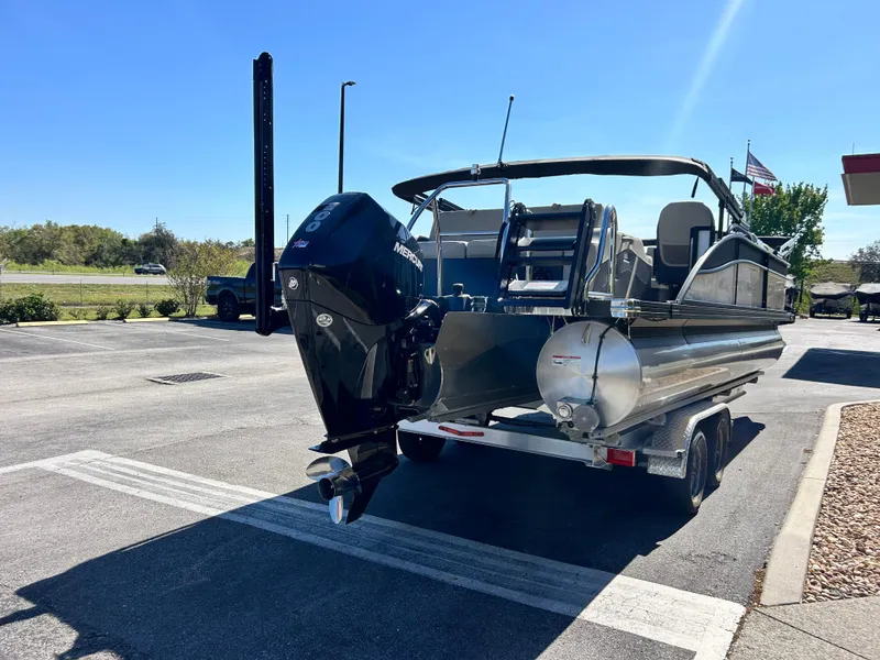 Slide: The Image of 2022 Barletta C24UC pontoon boat on trailer, parked outdoors under clear blue sky. - 11