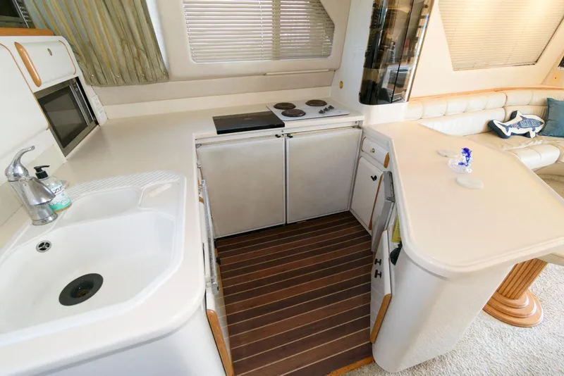Slide: The Image of Interior of 1995 Sea Ray 500 Sedan Bridge yacht kitchen with sink, stove, and seating area. - 18