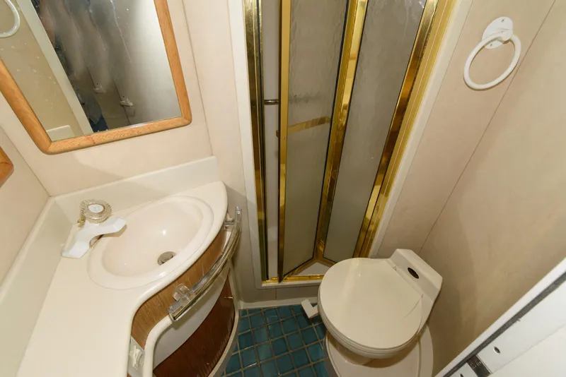 Slide: The Image of Bathroom interior of 1995 Sea Ray 500 Sedan Bridge yacht, featuring sink, toilet, and shower. - 25