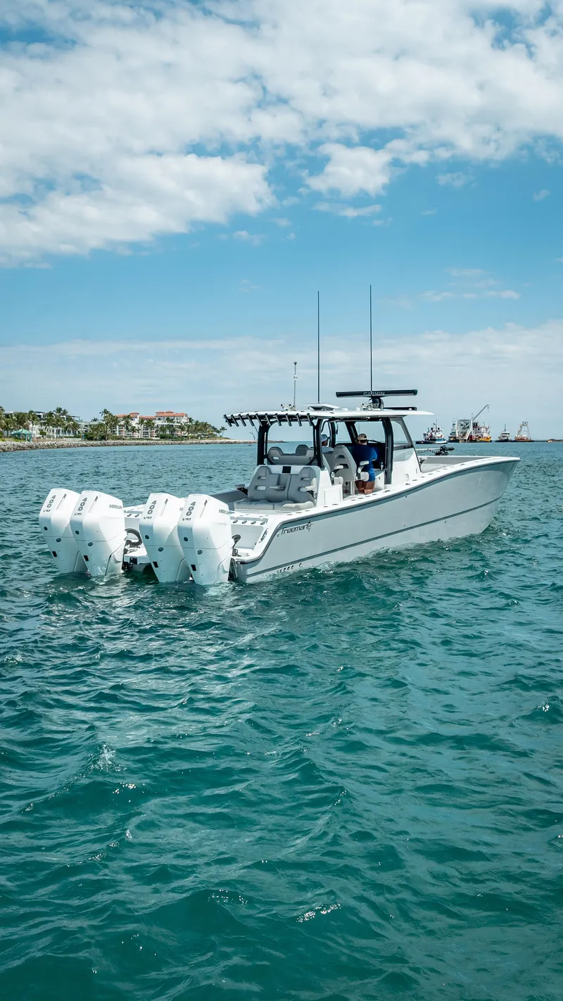 Slide: The Image of 2024 Freeman 43 boat on open water with four engines, under a partly cloudy sky. - 10