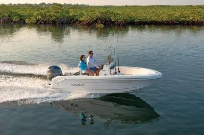 Slide: The Image of 2025 Robalo R160 Center Console boat cruising on calm water with two passengers. - 11