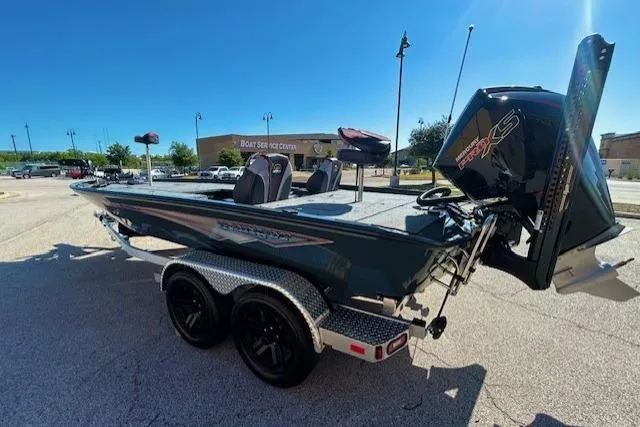 Slide: The Image of 2025 Ranger ALPHA 208 boat on trailer, parked outdoors under clear blue sky. - 2
