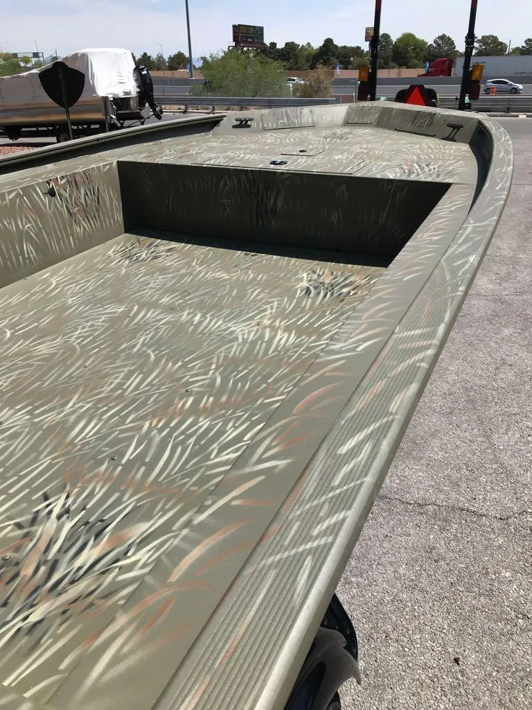 Slide: The Image of 2025 Tracker Grizzly 1754 Jon boat with camouflage pattern, parked outdoors. - 2