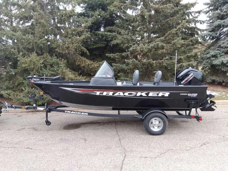 The Image of 2025 Tracker Pro Guide V-16 WT boat on trailer, parked near trees. - 0