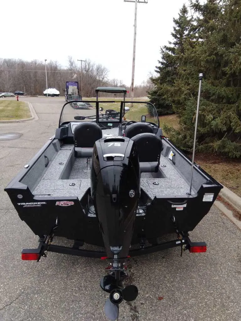Slide: The Image of 2025 Tracker Pro Guide V-16 WT boat with outboard motor, parked on a road. - 5