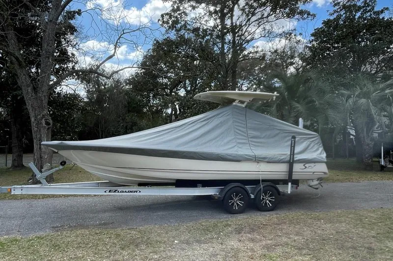 Slide: The Image of 2015 Scout 251 XS boat covered on trailer, parked outdoors. - 5