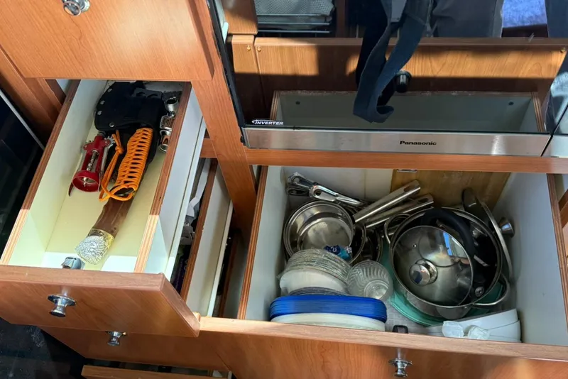 Slide: The Image of Open kitchen drawers on a 2008 Luhrs 35 Convertible, showing utensils and cookware. - 13