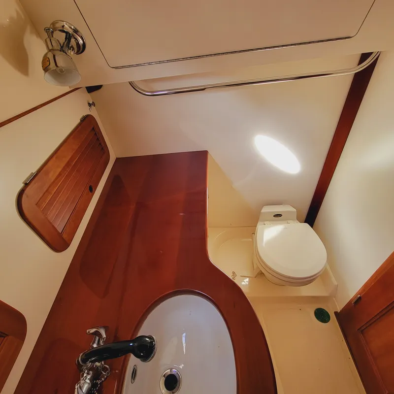Slide: The Image of 1999 Hinckley Picnic Boat Classic bathroom with wooden accents and compact design. - 23