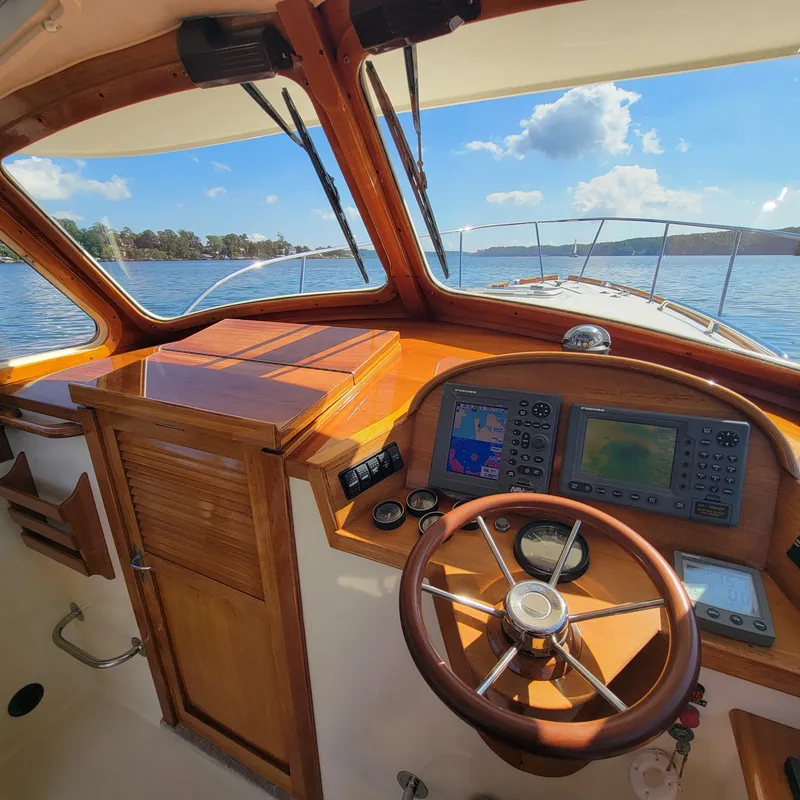 Slide: The Image of 1999 Hinckley Picnic Boat Classic helm with wooden dashboard and steering wheel on a sunny day. - 3