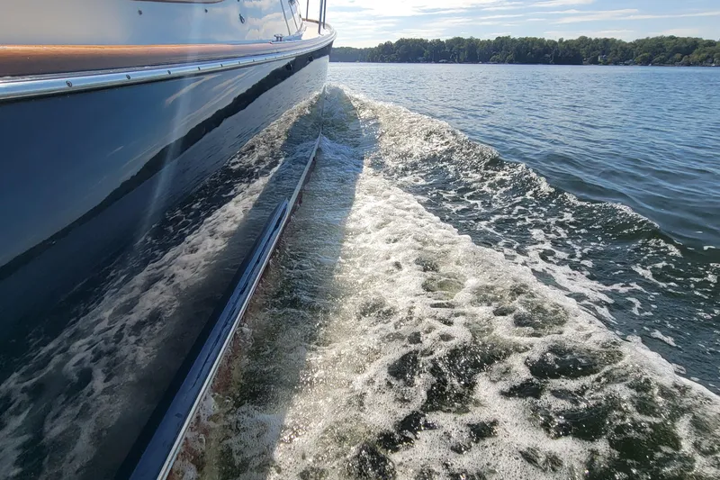 Slide: The Image of Hinckley Picnic Boat Classic 1999 cruising on a sunny lake, creating a gentle wake. - 4