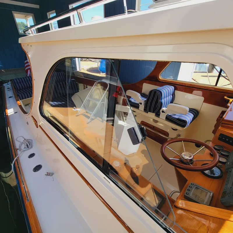 Slide: The Image of 1999 Hinckley Picnic Boat Classic interior with wooden steering wheel and striped seating. - 42