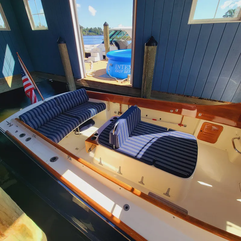 Slide: The Image of 1999 Hinckley Picnic Boat Classic with striped seating in a boathouse. - 44