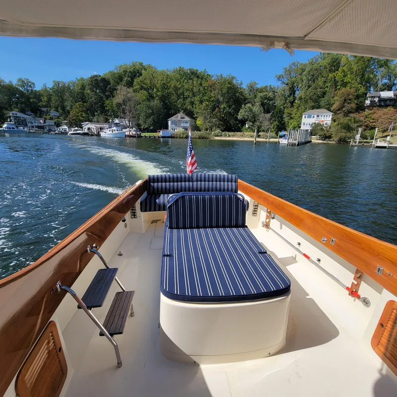 Slide: The Image of 1999 Hinckley Picnic Boat Classic cruising on a scenic river with striped seating. - 46