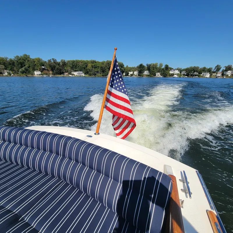 Slide: The Image of 1999 Hinckley Picnic Boat Classic cruising with American flag on lake. - 6
