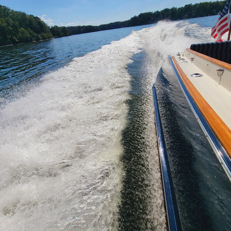 Slide: The Image of 1999 Hinckley Picnic Boat Classic cruising on a scenic lake, leaving a wake. - 7