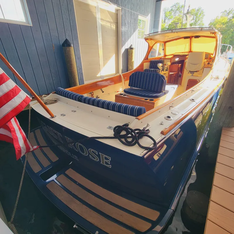 Slide: The Image of 1999 Hinckley Picnic Boat Classic docked, featuring elegant design and American flag. - 9