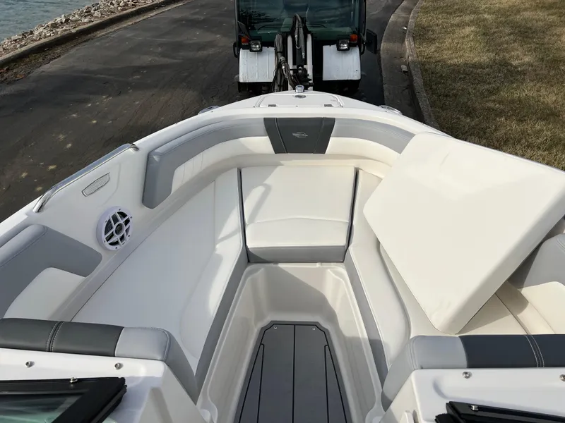 Slide: The Image of 2025 Chaparral 21 SSi boat interior with white and gray seating, docked on a trailer. - 11