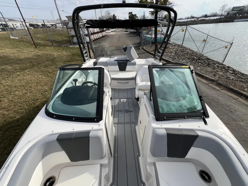 Slide: The Image of 2025 Chaparral 21 SSi boat interior with open windshield, docked by a lakeside. - 13