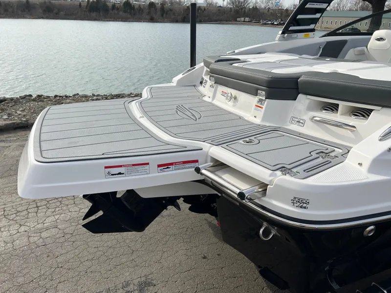 Slide: The Image of 2025 Chaparral 21 SSi boat with swim platform, docked by a calm lake. - 4