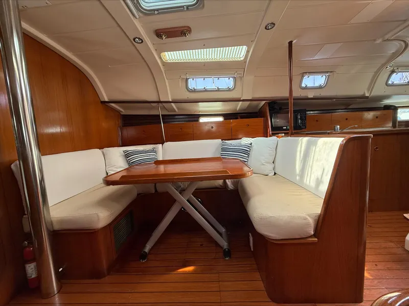 Slide: The Image of Interior of 1993 Beneteau Oceanis 400 sailboat with wooden dining area and cushioned seating. - 12